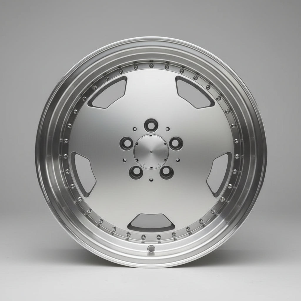 A large, polished silver multi-spoke alloy wheel rim displayed on top of cardboard boxes in a warehouse setting.