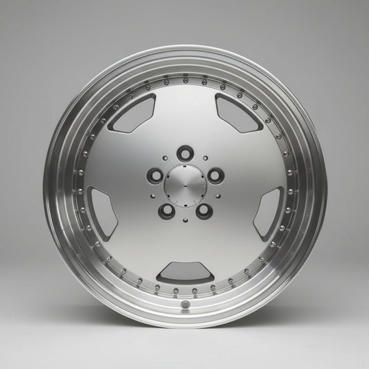 A large, polished silver multi-spoke alloy wheel rim displayed on top of cardboard boxes in a warehouse setting.