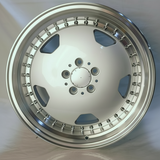 A polished silver multi-spoke alloy wheel rim with a deep lip and decorative lug details, photographed against a light gray fabric background.